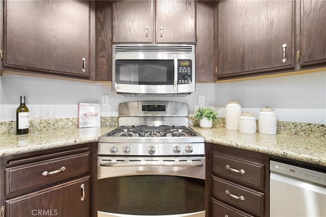 kitchen featuring dark brown cabinets, light stone counters, and stainless steel appliances