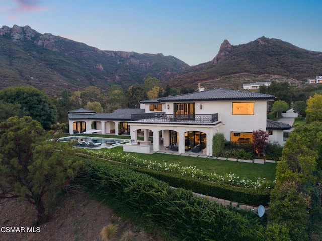 back of house with a mountain view, a yard, a balcony, and a patio