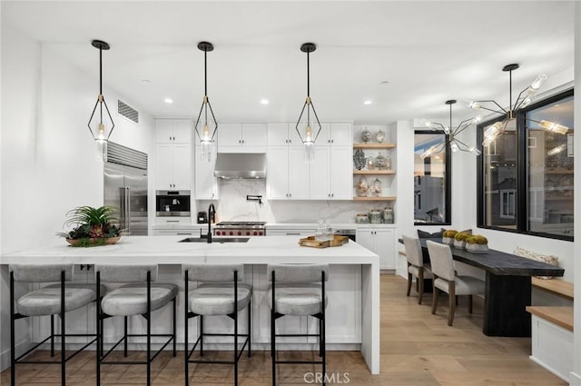 kitchen featuring appliances with stainless steel finishes, a peninsula, extractor fan, a kitchen bar, and open shelves