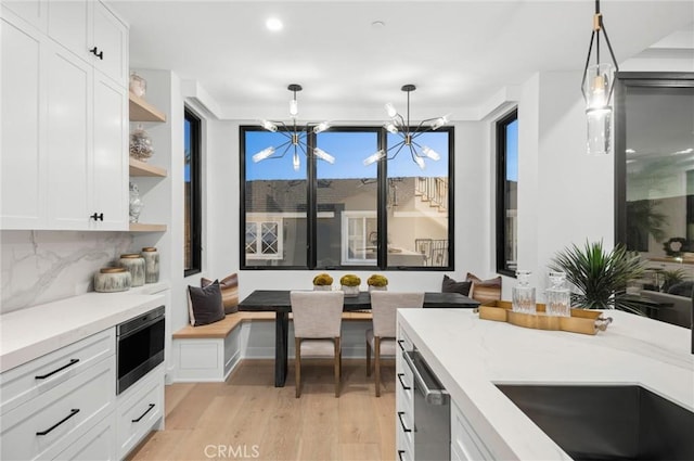 kitchen with light wood finished floors, open shelves, breakfast area, white cabinetry, and a chandelier