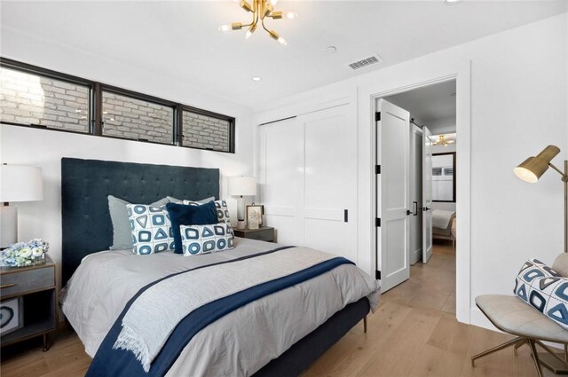 bedroom featuring a notable chandelier, light hardwood / wood-style floors, and a closet