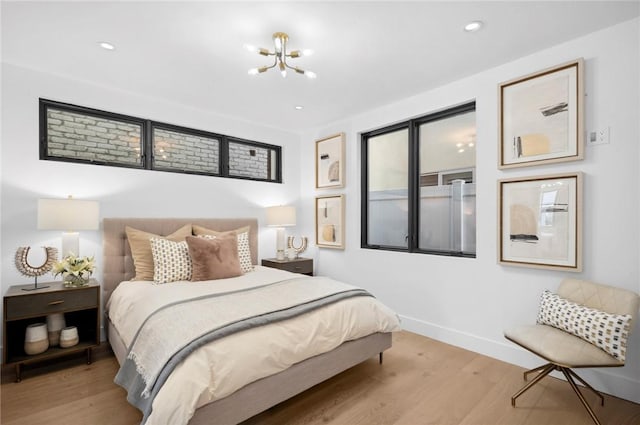 bedroom with light wood-type flooring, baseboards, a notable chandelier, and recessed lighting