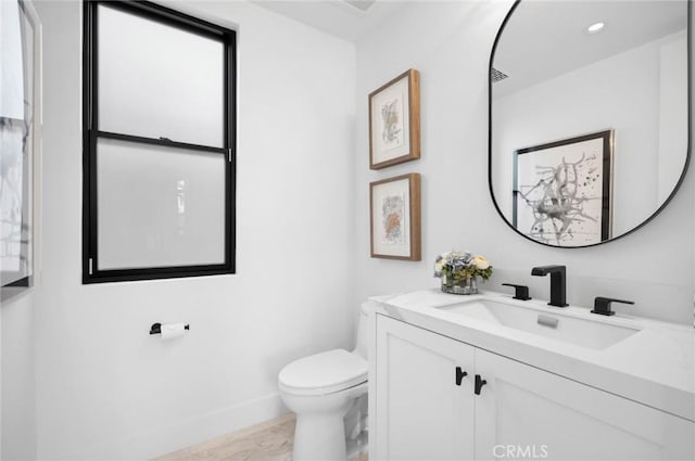 bathroom featuring vanity, toilet, and baseboards