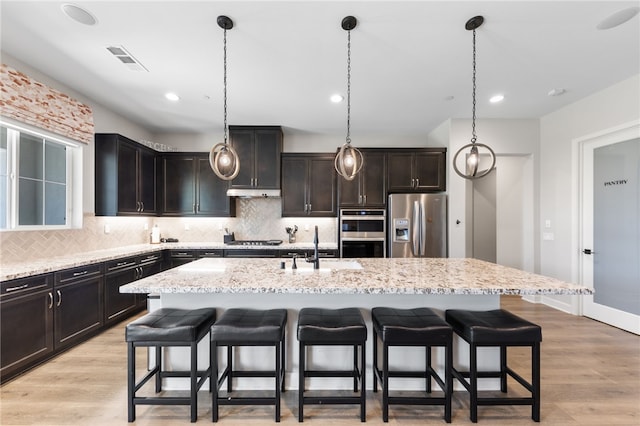 7631 Capstone Ct, Riverside, CA 92506 - kitchen with stainless steel appliances, a sink, a breakfast bar area, tasteful backsplash, and recessed lighting
