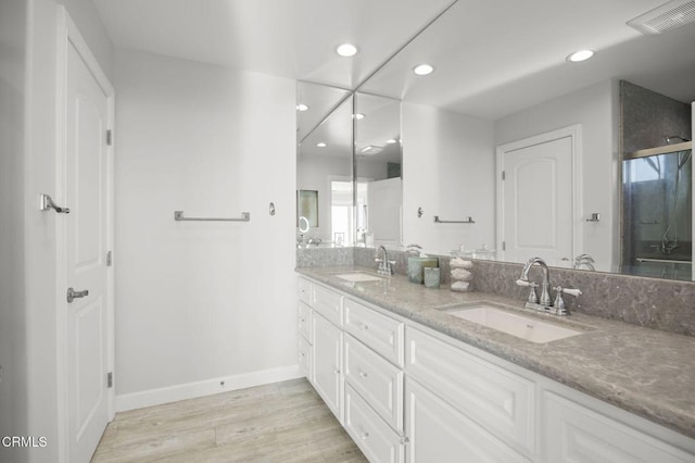 bathroom with a sink, recessed lighting, double vanity, and wood finished floors