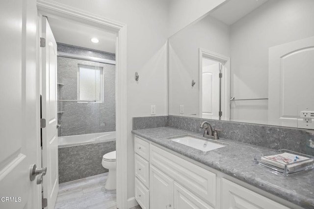 bathroom featuring vanity, toilet, and a combined bath / shower with marble appearance