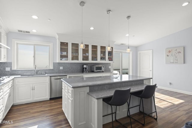 kitchen with a sink, a center island, white cabinetry, glass insert cabinets, and stainless steel dishwasher