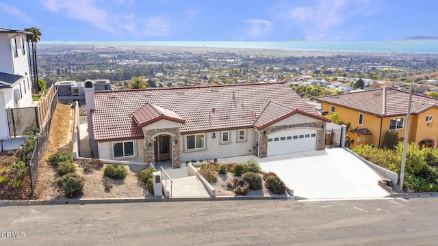 mediterranean / spanish-style home with a tiled roof, stone siding, concrete driveway, an attached garage, and fence