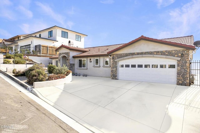 mediterranean / spanish home with stone siding, driveway, stucco siding, an attached garage, and a tile roof