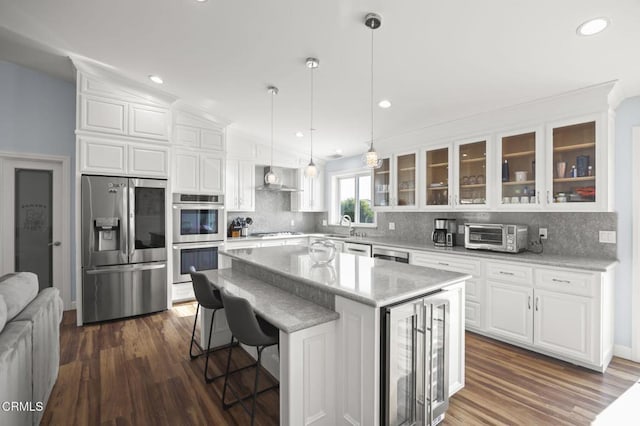 kitchen featuring a kitchen island, appliances with stainless steel finishes, decorative light fixtures, white cabinetry, and glass insert cabinets