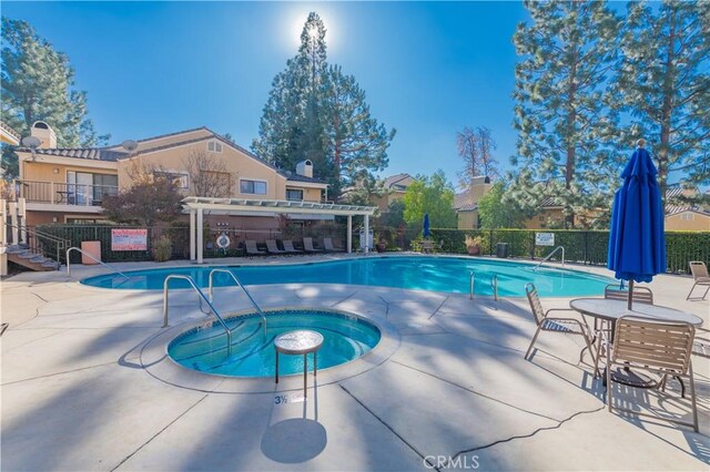 view of pool with a pergola, a community hot tub, and a patio