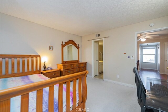 bedroom with a textured ceiling, ensuite bathroom, ceiling fan, and light colored carpet