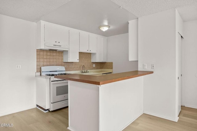 kitchen featuring decorative backsplash, white gas range, sink, light hardwood / wood-style flooring, and white cabinets