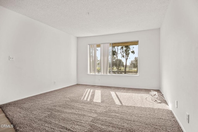 carpeted empty room with a textured ceiling and baseboards