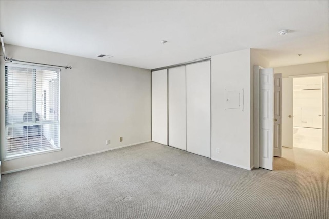 unfurnished bedroom with light colored carpet and a closet