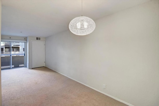 empty room with light colored carpet and a chandelier