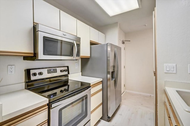 kitchen with white cabinetry, appliances with stainless steel finishes, and light wood-type flooring