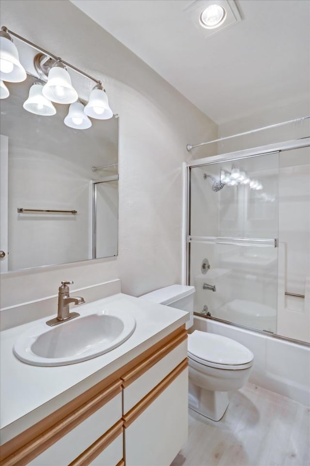 full bathroom featuring bath / shower combo with glass door, vanity, and toilet