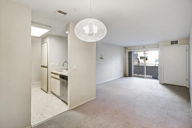 kitchen featuring decorative light fixtures, dishwasher, sink, a notable chandelier, and light carpet