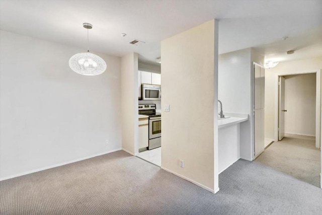 kitchen featuring light carpet, hanging light fixtures, stainless steel appliances, and white cabinets