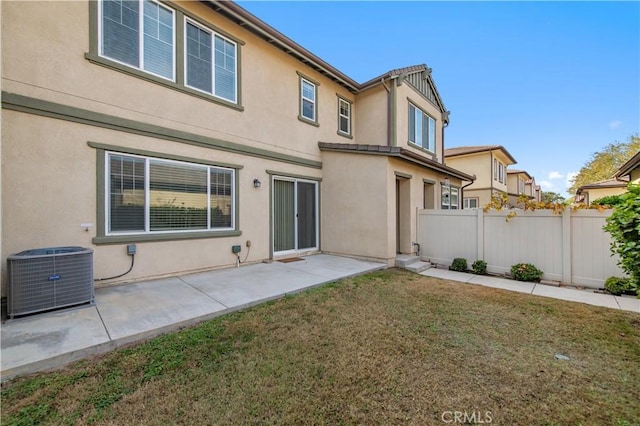 rear view of house featuring central air condition unit, a patio area, and a lawn