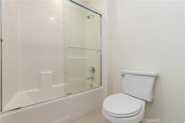 bathroom with tile patterned floors, toilet, and bath / shower combo with glass door