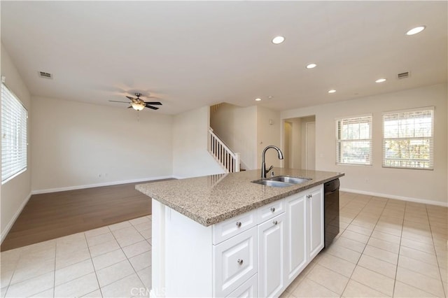 kitchen with a center island with sink, sink, ceiling fan, black dishwasher, and white cabinetry