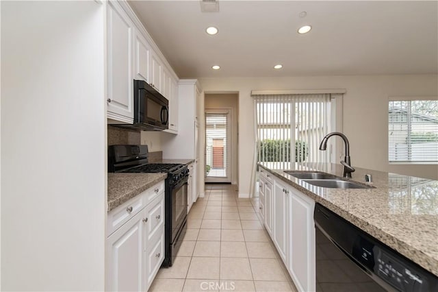 kitchen featuring light stone countertops, white cabinetry, sink, light tile patterned floors, and black appliances