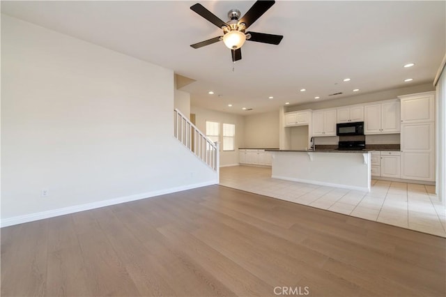 unfurnished living room featuring ceiling fan, sink, and light wood-type flooring