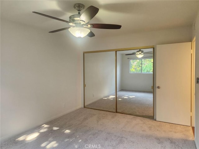 unfurnished bedroom featuring ceiling fan, a closet, and light carpet