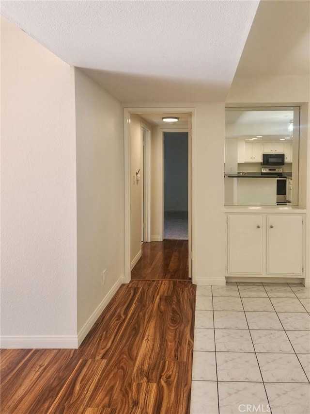 corridor featuring a textured ceiling and light hardwood / wood-style flooring