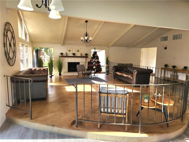 living room with hardwood / wood-style floors, lofted ceiling with beams, a fireplace, and a chandelier