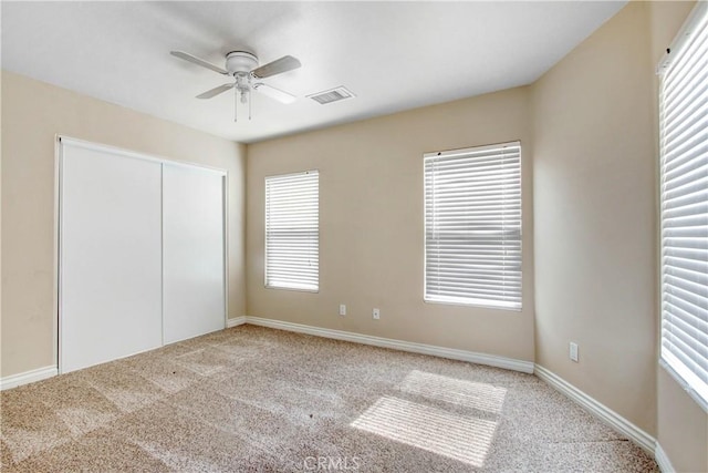 unfurnished bedroom with multiple windows, ceiling fan, a closet, and light colored carpet