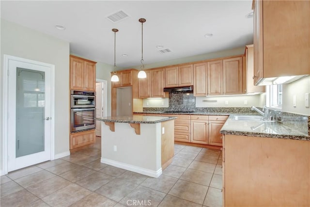 kitchen featuring light stone countertops, sink, black gas cooktop, double oven, and decorative light fixtures