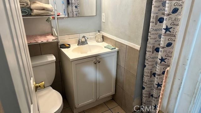 bathroom featuring vanity, toilet, and tile walls