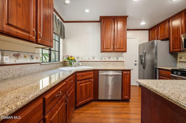 kitchen featuring dark hardwood / wood-style flooring, light stone counters, crown molding, and appliances with stainless steel finishes