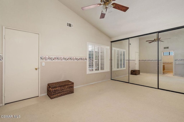 unfurnished bedroom featuring ceiling fan, light colored carpet, high vaulted ceiling, and a closet