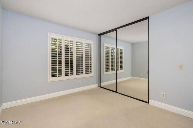 unfurnished bedroom with a closet and light colored carpet