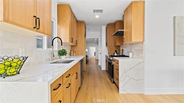 kitchen featuring light stone countertops, appliances with stainless steel finishes, extractor fan, sink, and light wood-type flooring