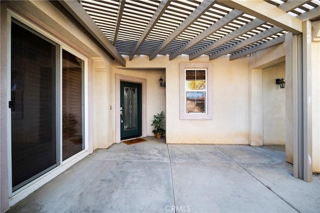 view of exterior entry with a pergola and a patio area