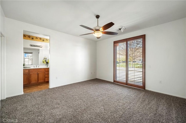 unfurnished bedroom featuring ceiling fan, carpet, connected bathroom, and sink