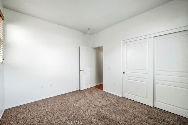 unfurnished bedroom featuring dark carpet and a closet