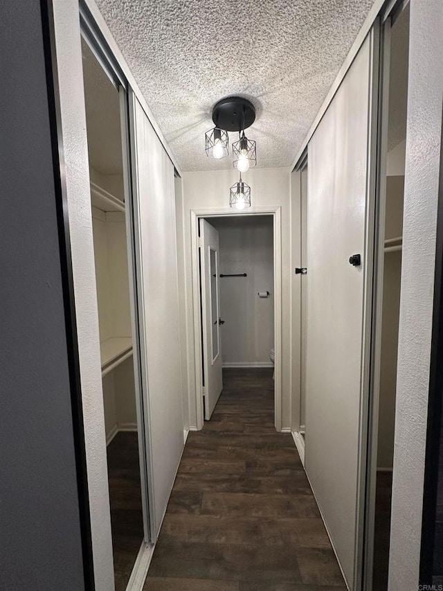 corridor with dark hardwood / wood-style flooring and a textured ceiling