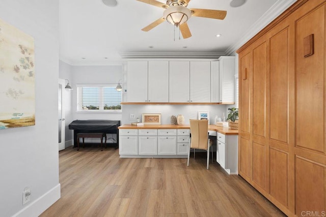 kitchen featuring light wood-type flooring, built in desk, white cabinetry, and crown molding