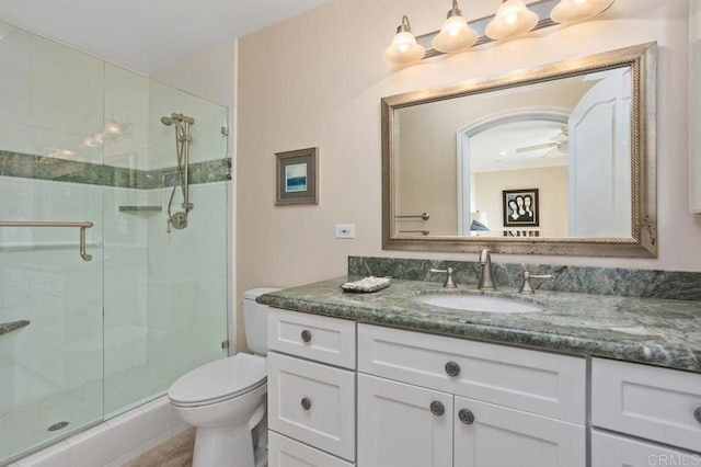 bathroom with an enclosed shower, vanity, toilet, and ceiling fan