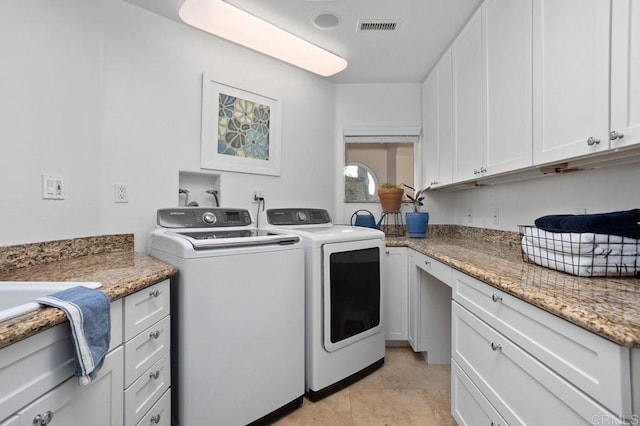 clothes washing area with cabinets, light tile patterned floors, and washing machine and clothes dryer