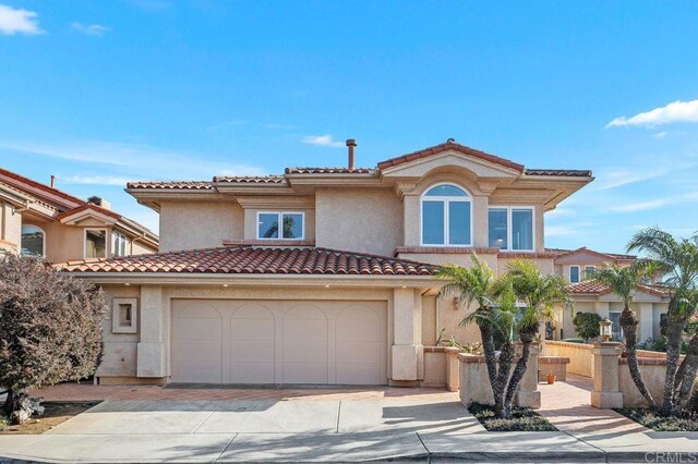 mediterranean / spanish-style house featuring driveway, a tiled roof, and stucco siding