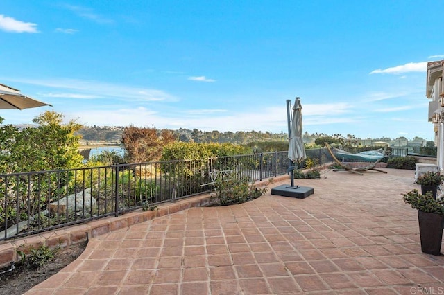 view of patio / terrace featuring a water view and fence