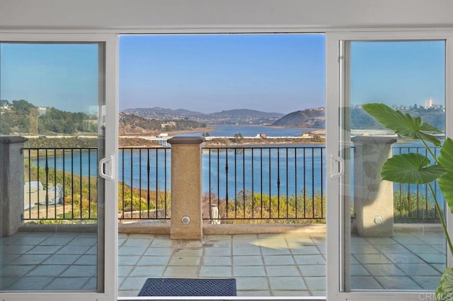 doorway with tile patterned floors, a healthy amount of sunlight, and a water and mountain view