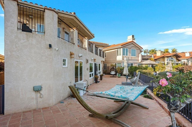 rear view of property featuring a patio area, a residential view, fence, and stucco siding